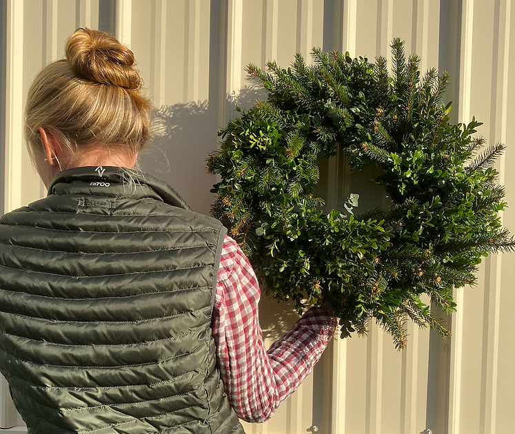 Woman holding a wreath of mixed Christmas greens