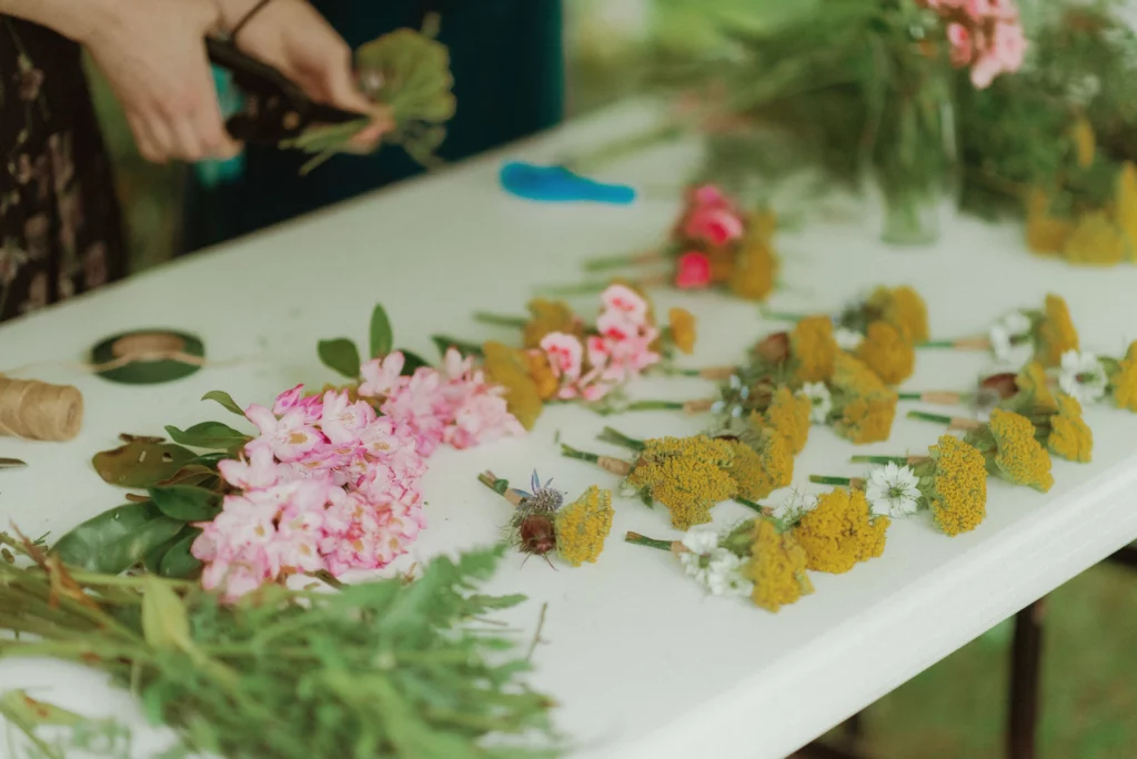 Folding table is set with lots of precut fresh flowers ready to be made into DIY wedding flowers.