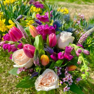 Spring Easter Flowers arrangement sitting in a bright green field with daffodils