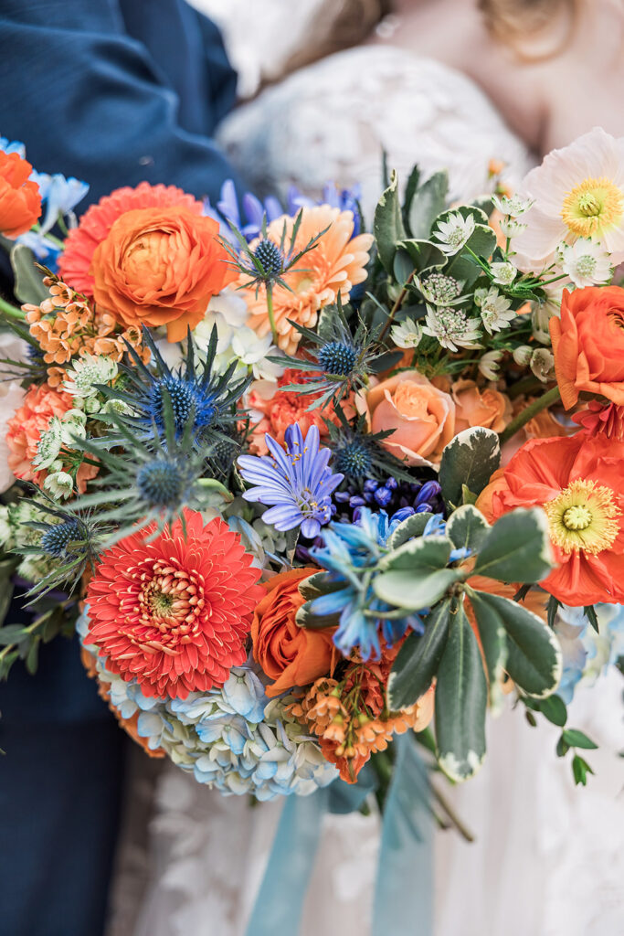 Closeup of spring wedding bouquet in shades of orange and blue.