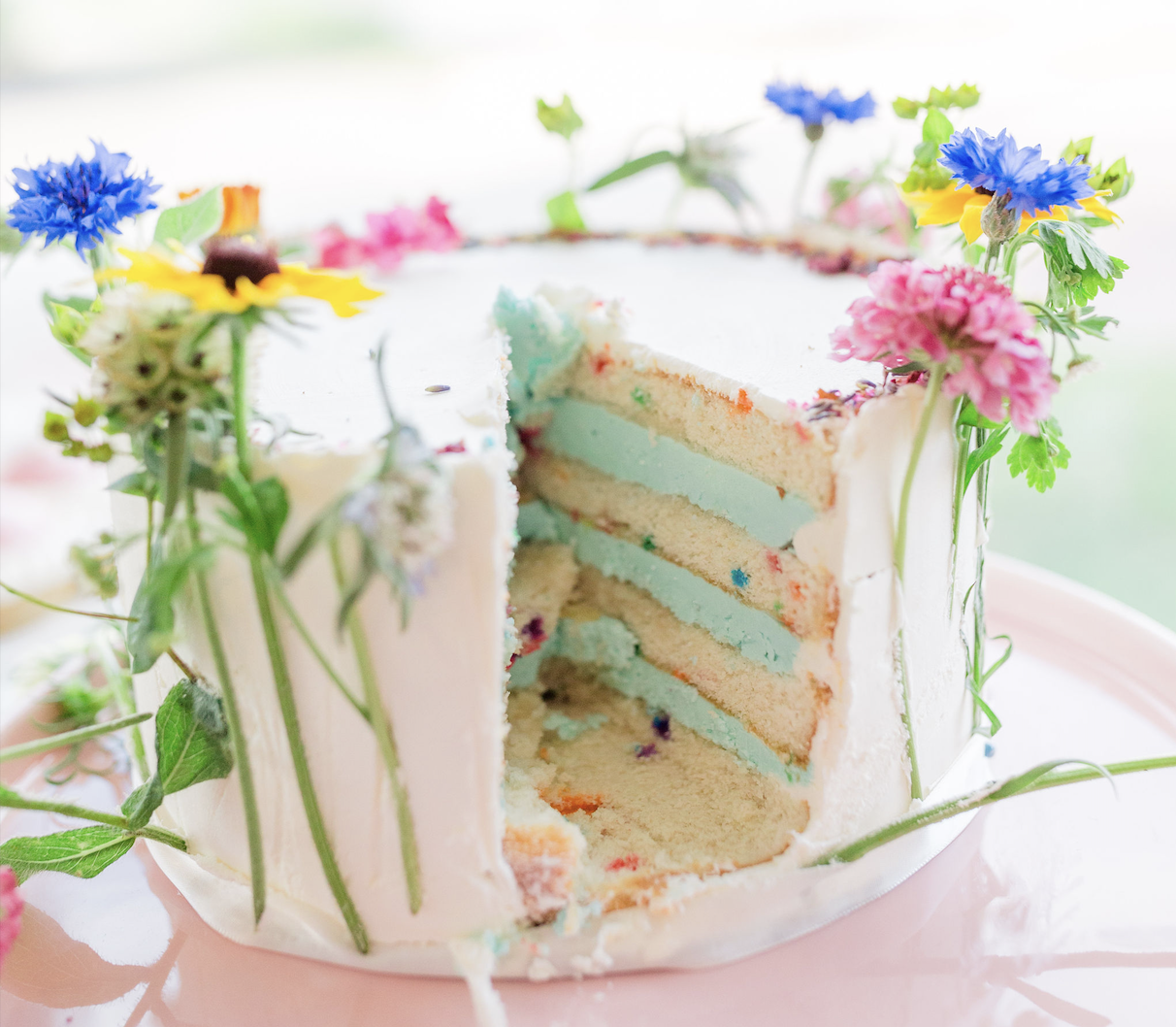 colorful flowers on wedding cake with bachelor buttons, black eyed susans and nigella pods