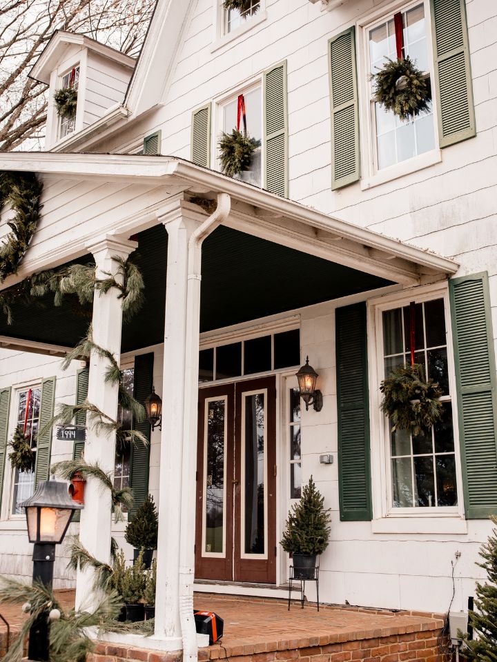christmas greenery on house with pillars and window decorations