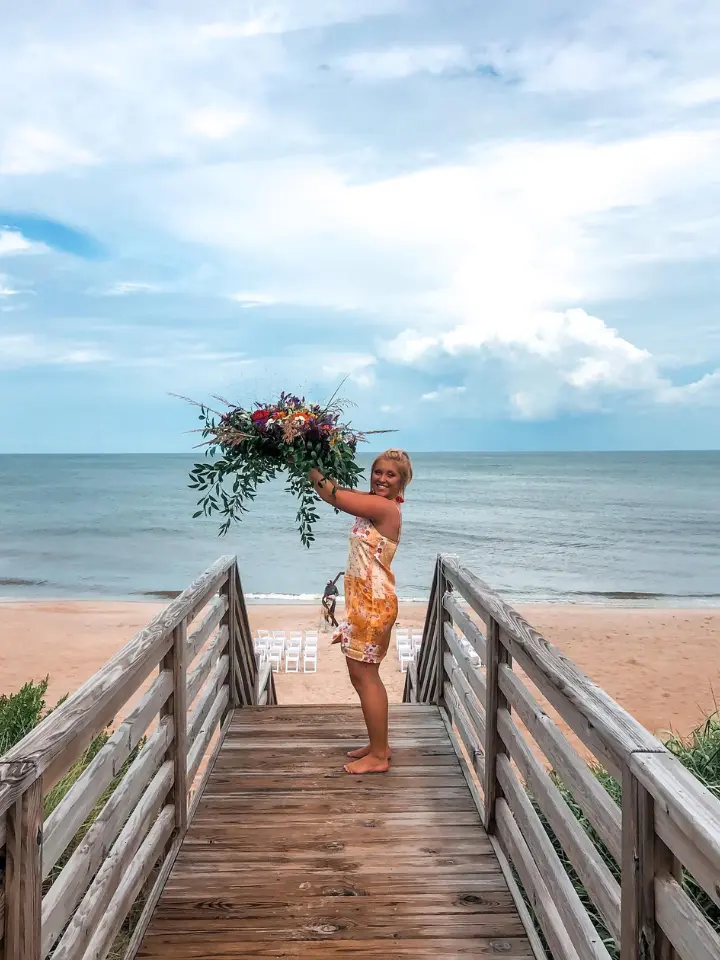 First Out of State Wedding with Lizzie holding arch piece on the beach