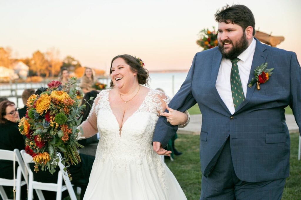 Bride and Groom smile as they walk down the aisle after their waterfront wedding ceremony.