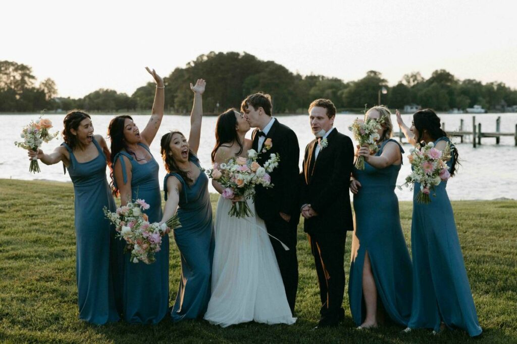 Wedding party celebrates with bride and groom, all holding bouquets.