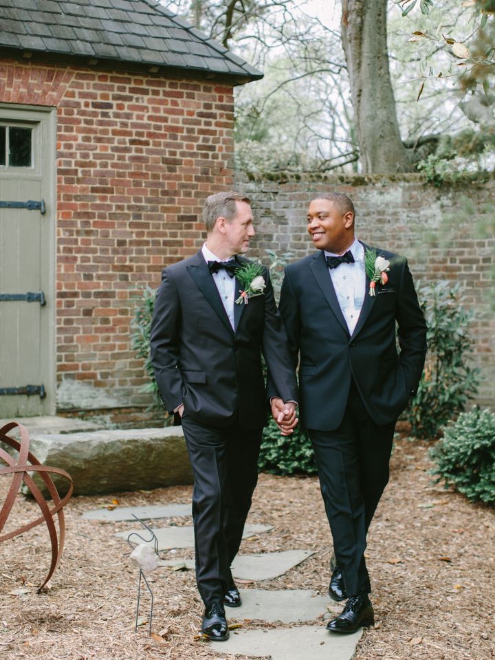 Grooms in black tuxes stroll through the brick courtyard.