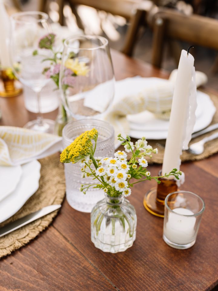 Bud vase with small daisies on a harvest table.