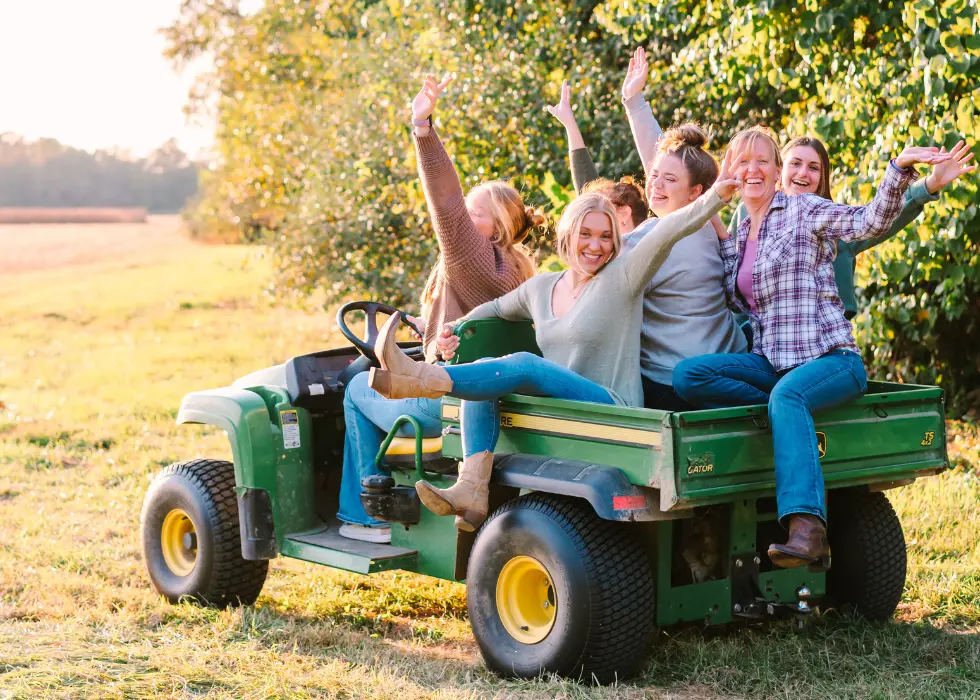 The girls at Wildly Native laughing all piled into the gator driving across the farm field