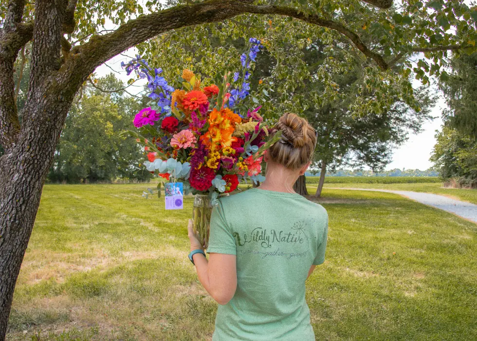 Founder, Liza, carrying a vase of wildflowers