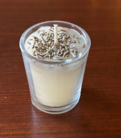 Closeup of votive candle with lavender on top.