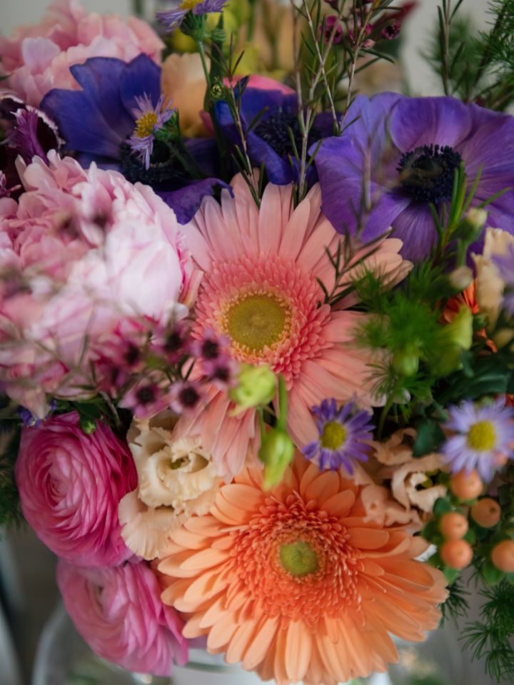Close up of pink, coral, and purple flowers in bridal bouquet including peonies
