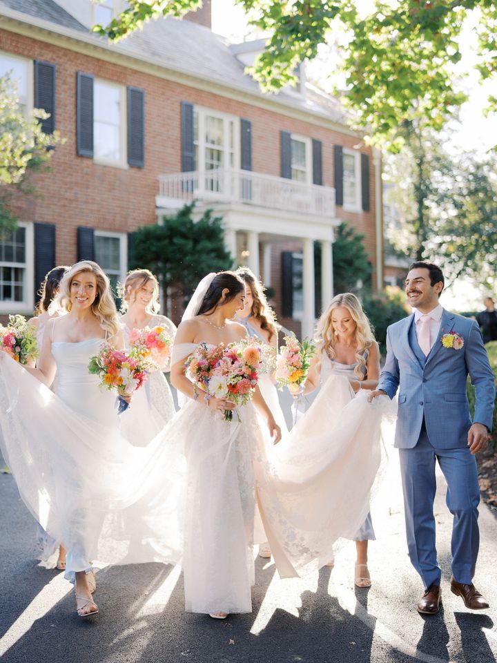 Bride and her bridal party walk with their florals in front of Brittland Manor.