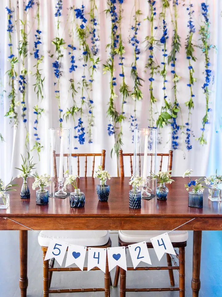hodsonboathouse2 A blue and white flower backdrop behind a wood sweetheart table setup