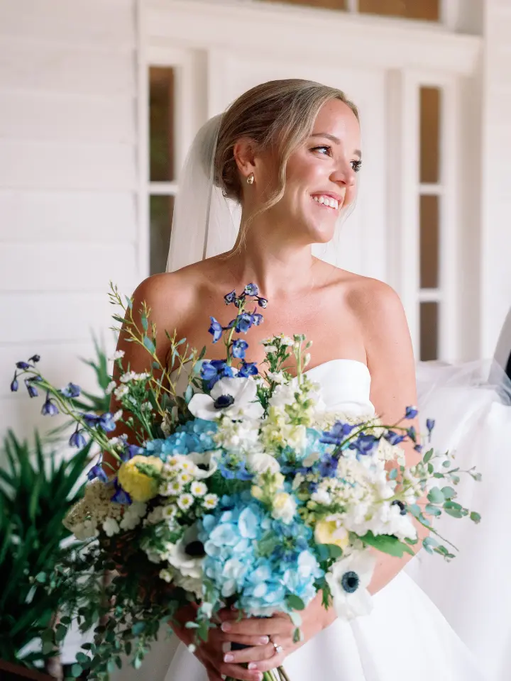 springbluewhite_wylderhotel3 Bride smiling while holding a blue and white bouquet by Wildly Native Flower Farm