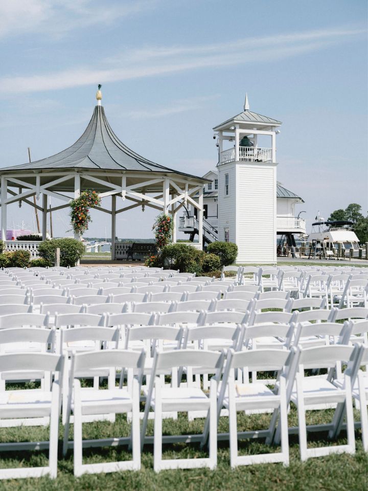 Rows of white chairs lined up for an outdoor wedding ceremony on the waterfront in St Michaels, Maryland.