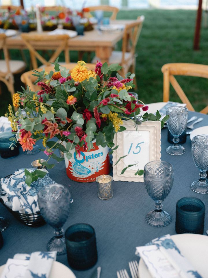 Blue linen on a round table with a vintage oyster tin floral centerpiece.