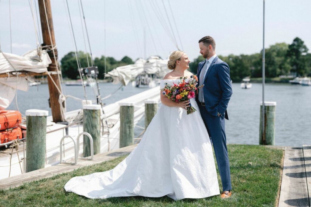 Bride and Groom pose with her summer wildflower bouquet at the waterfront at the Chesapeake Bay Maritime Museum.