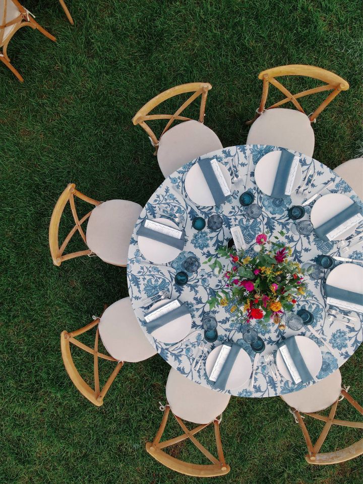 Overhead view of a round table with patterned blue and white linen and bright floral arrangement in the center.