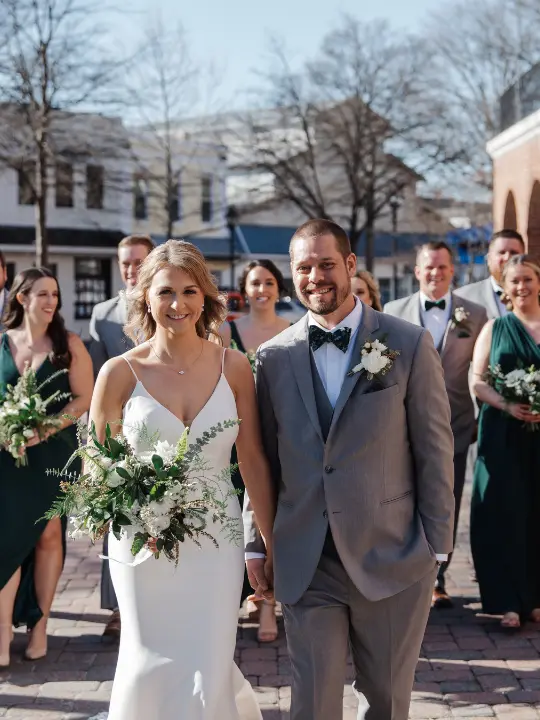 brideandgroomtidewaterinn Bride and groom smiling at the camera with wedding party behind them at Tidewater Inn