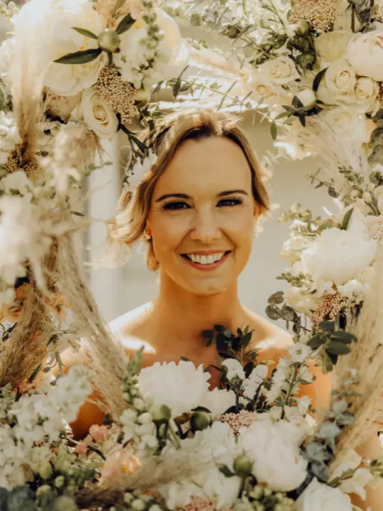 brideportraitsurroundedbywhiteflorals Bride smiling while surrounded by her bridesmaids white neutral floral bouquets