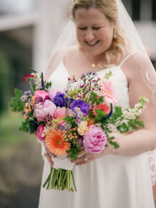 brightwildpurplepinkbouquet Bride looking down at her bouquet