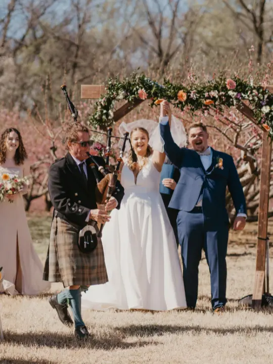 springpastelarbordecor bride and groom celebrating after ceremony with bagpiper exit