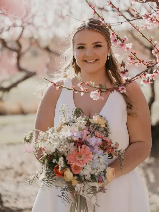 springpastelarrangementmilburnorchards bride holding spring pastel bouquet near cherry blossom branch