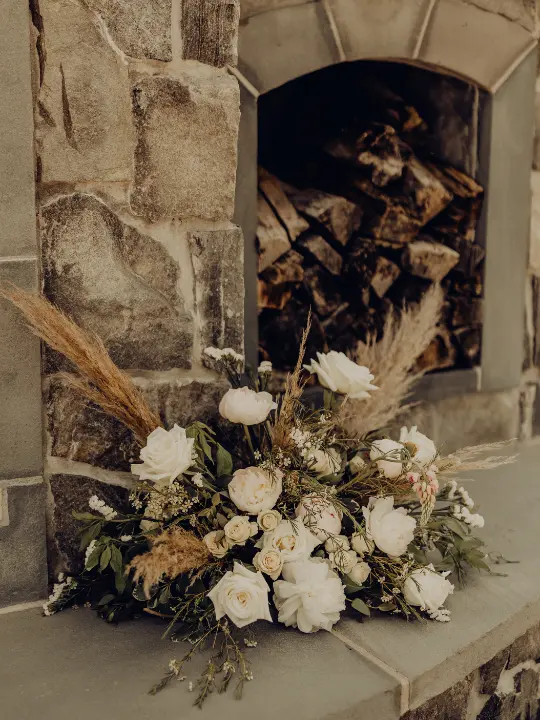 whiteandgrassarrangementatfireplace White arrangement on fireplace with plumes