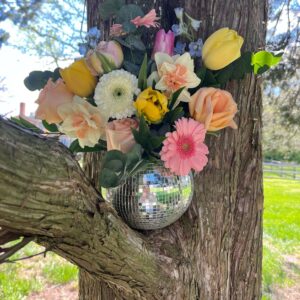 A spring colored florals disco ball arrangement in a tree.