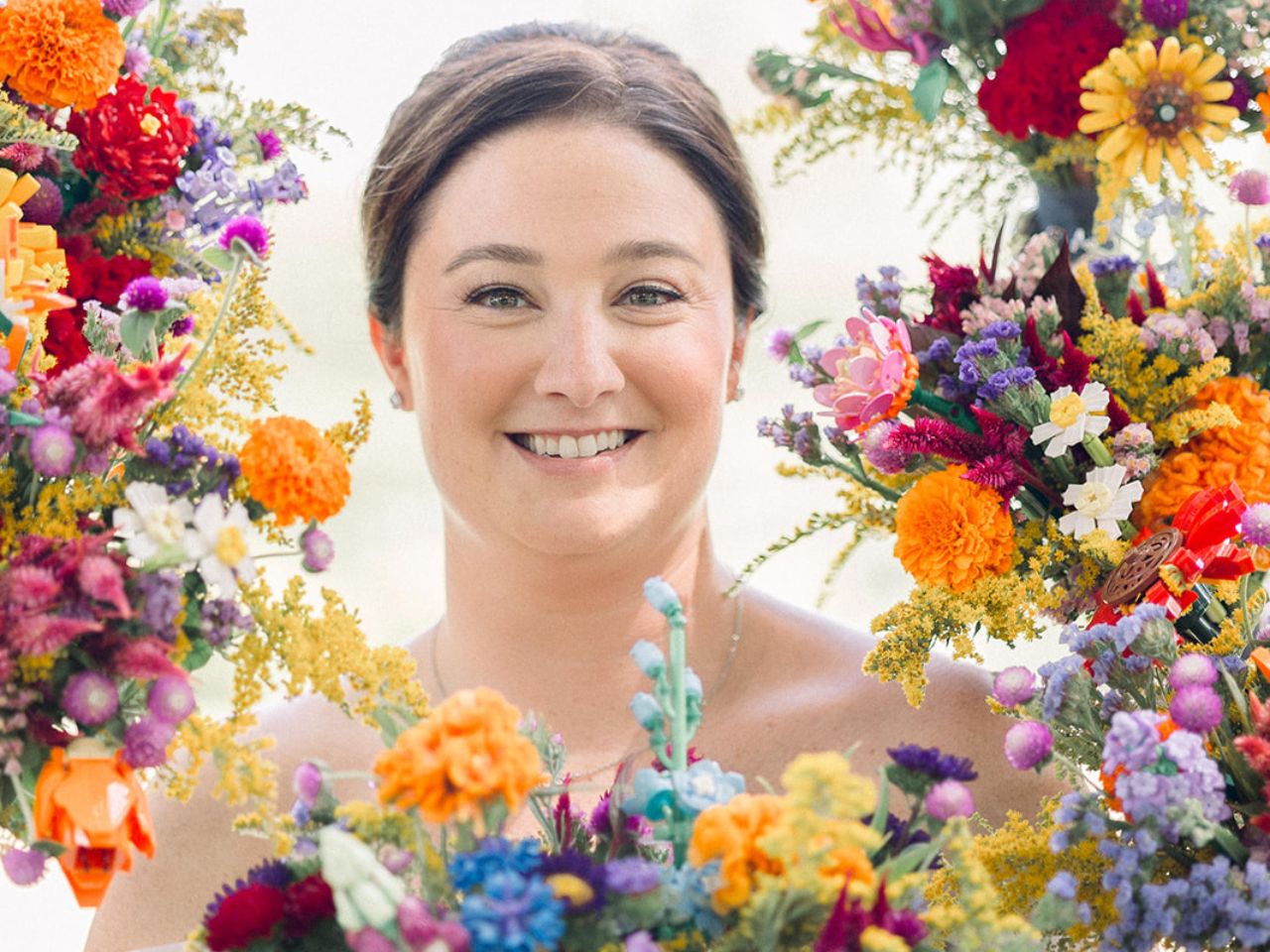 Bride smiles in a "frame" of flower bouquets with legos.