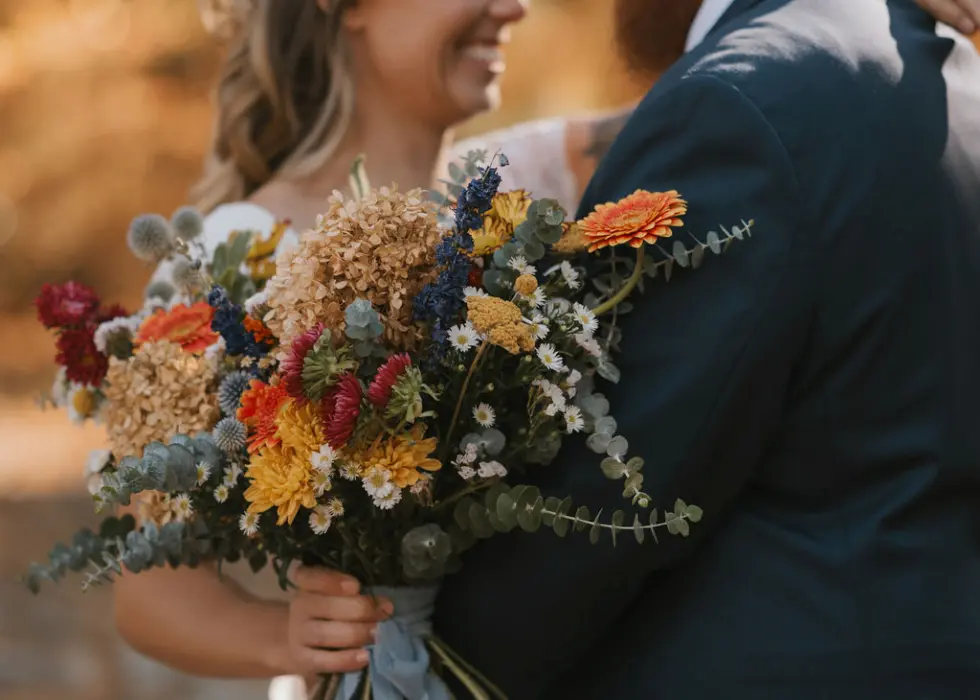 A wildly native bride holding a bouquet looking up at her husband