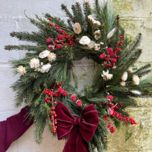 Christmas wreath with dried flowers and berries in red and white.