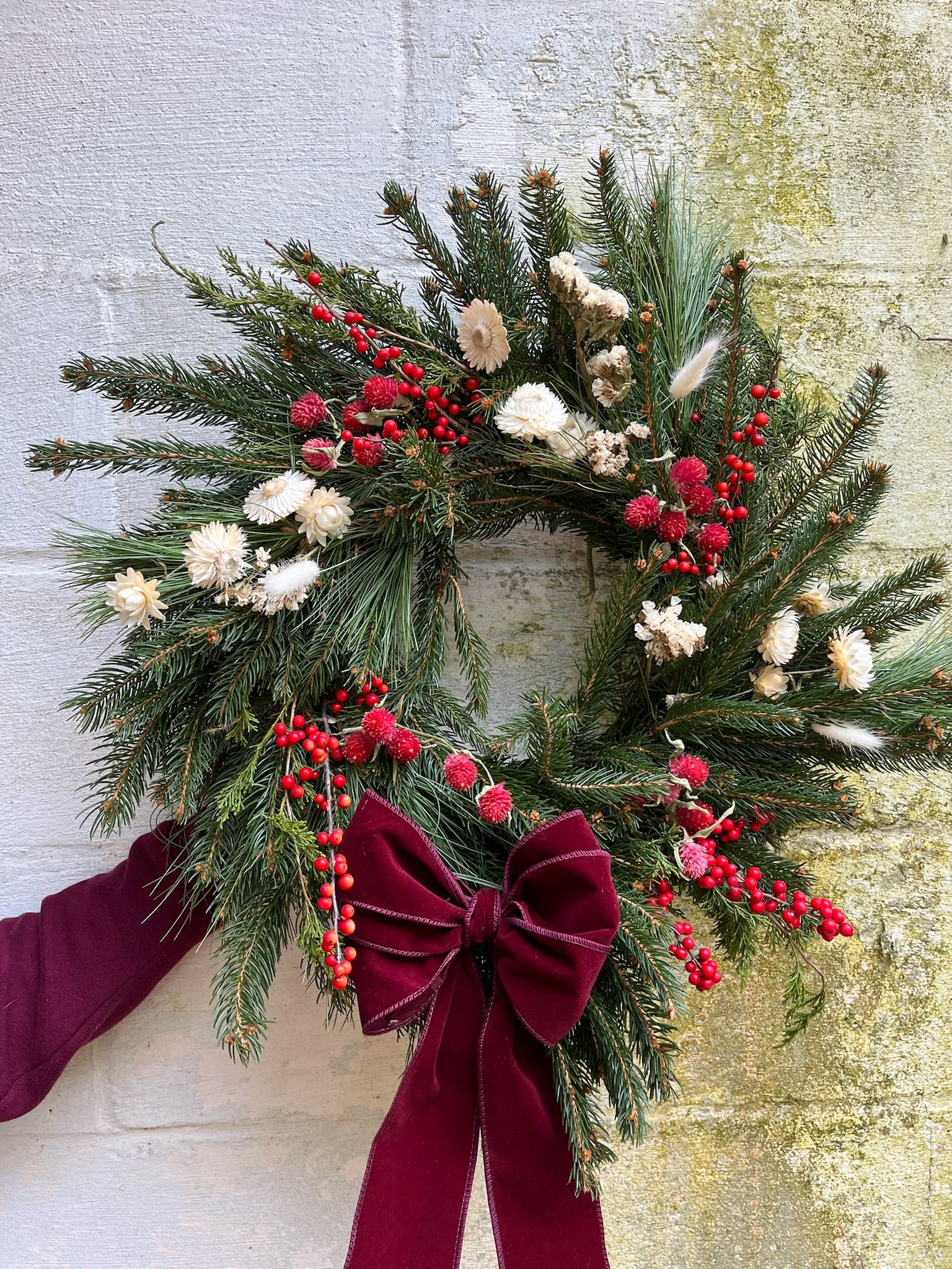 Christmas wreath with dried flowers and berries in red and white.