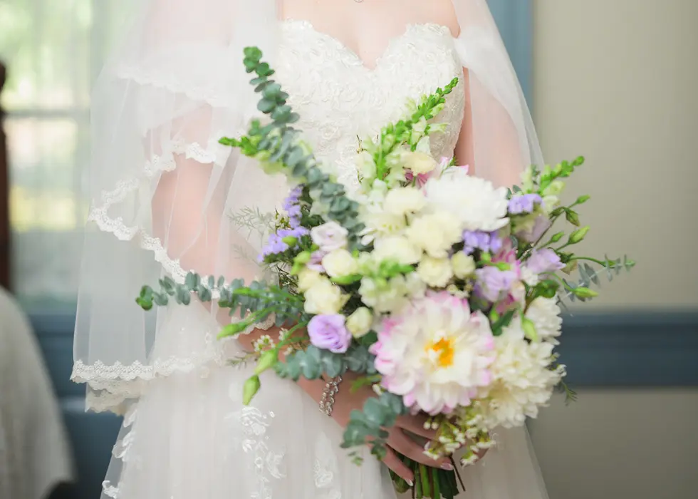 pastel bridal floral bouquet held by a bride wearing a veil