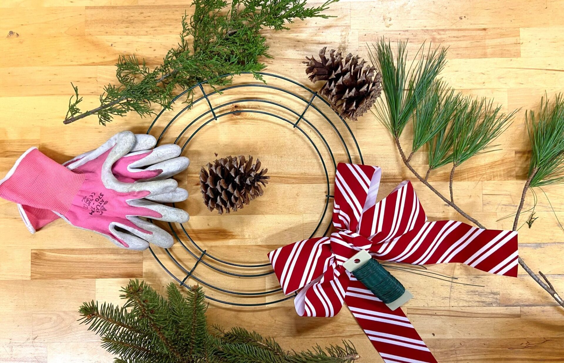 Wreath making supplies sit on a wooden table.