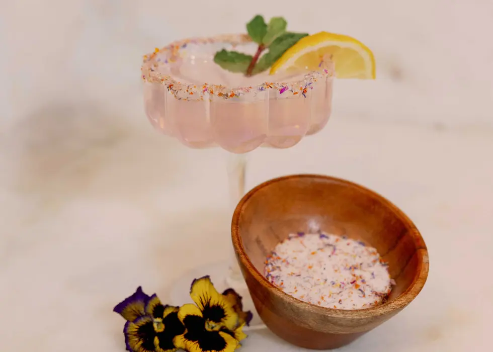A cocktail rimmed with floral salt by Wildly Native flower farm's Petal Pantry collection