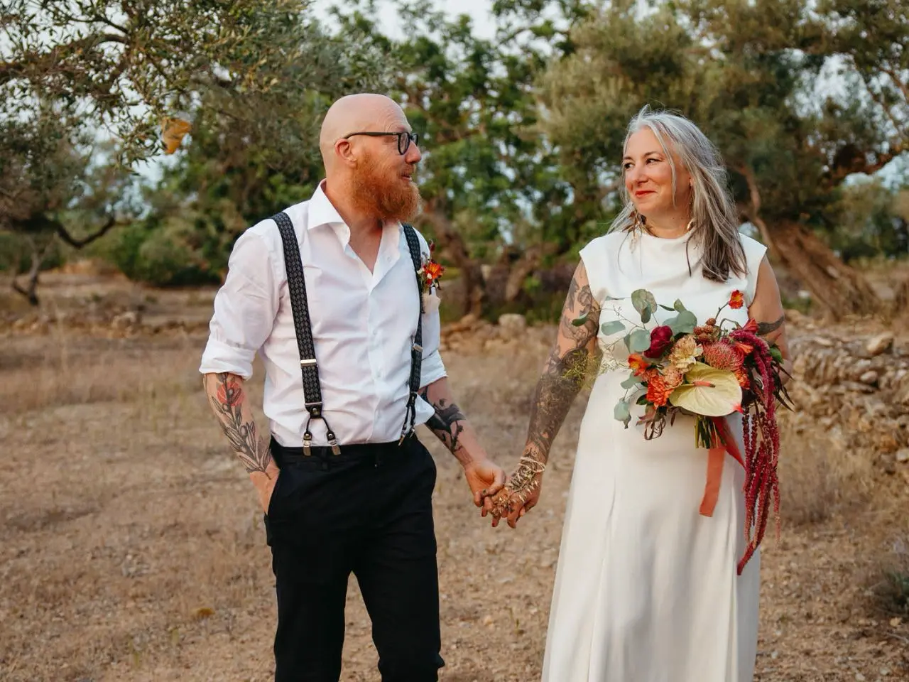 A bride and groom looking at each other while the bride holds her floral bouquet by Wildly Native Flower Farm
