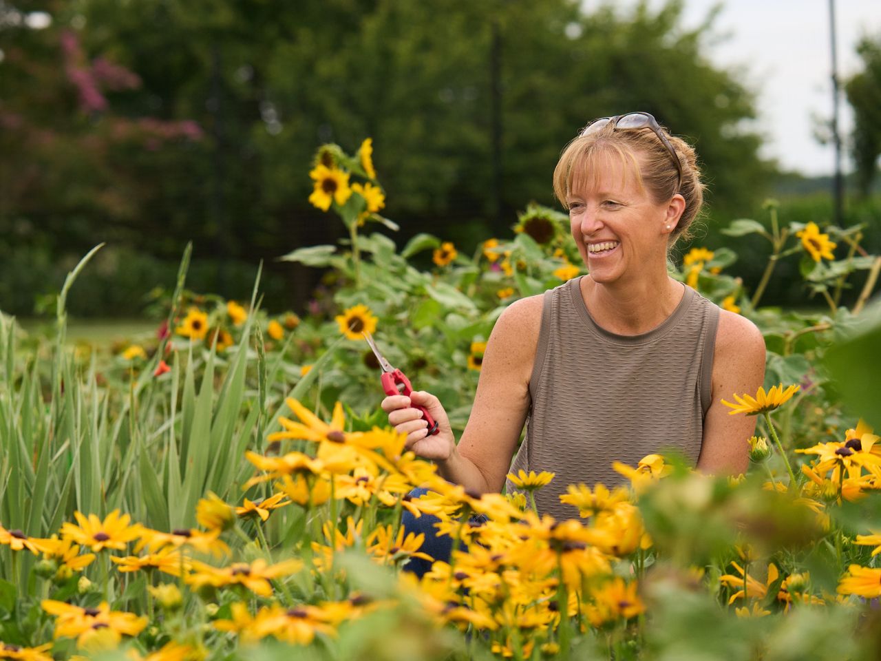 Liza sits in a row of black eyed susan cut flowers and smiles