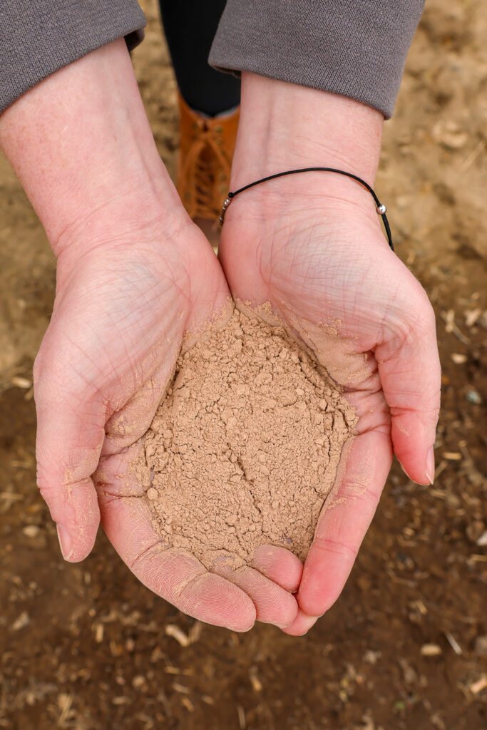 Two hands hold clay soil.