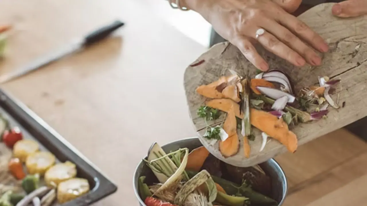 A person putting table scraps into a bowl ready to compost