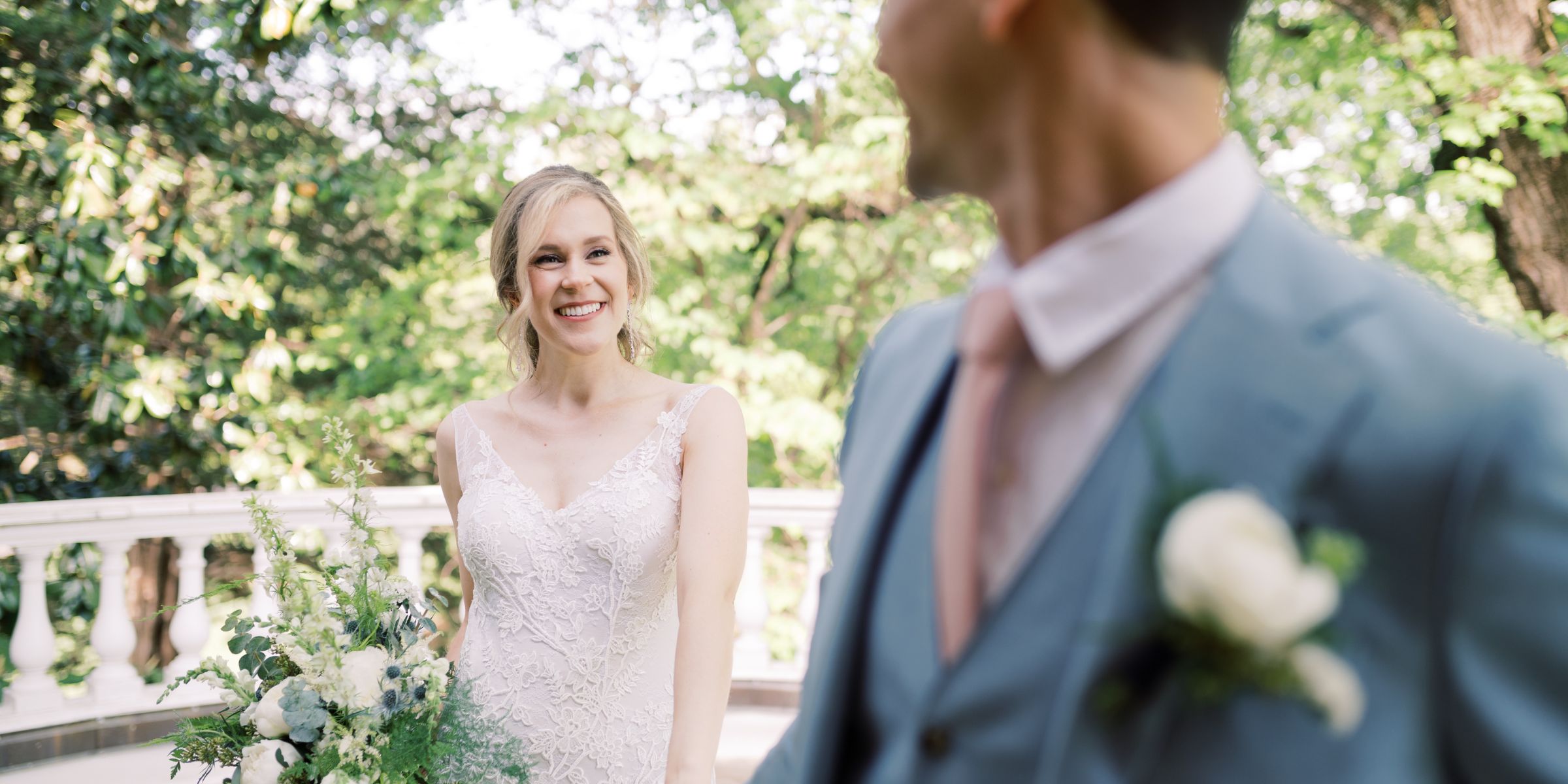 Bride and groom smile at each other outside.