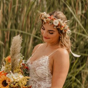 Bride has a flower crown with fresh and dried flowers, in dark orange, tan, and ivory