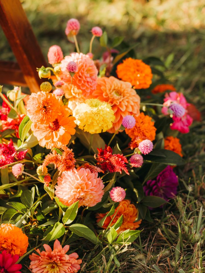 aisle florals citrus Flower arrangement sits at base of chair down the aisle at an outdoor wedding ceremony.