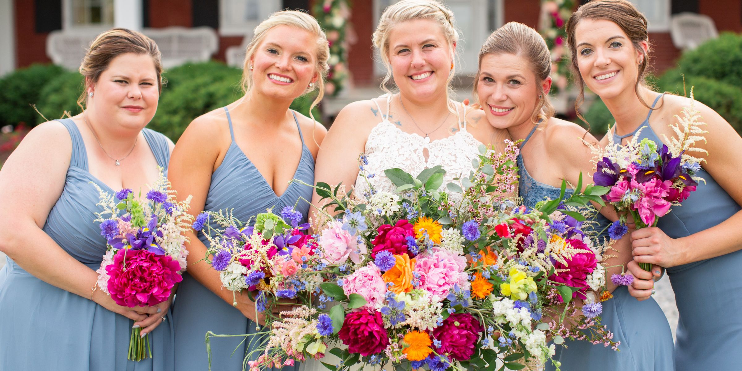 Bride and her bridesmaids hold colorful spring peony bouquets.