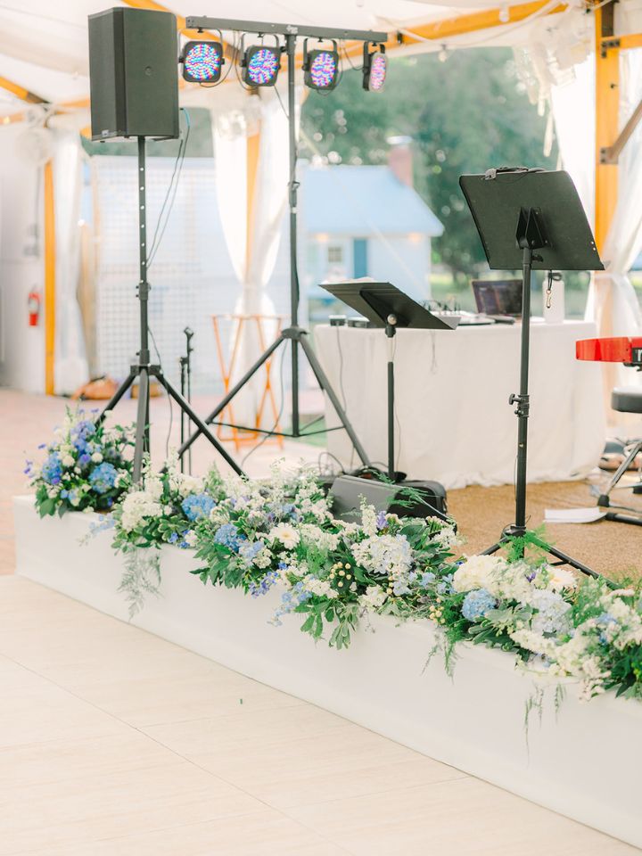 Blue and white flowers line the front edge of a white bandstand at Kent Island Resort wedding reception.