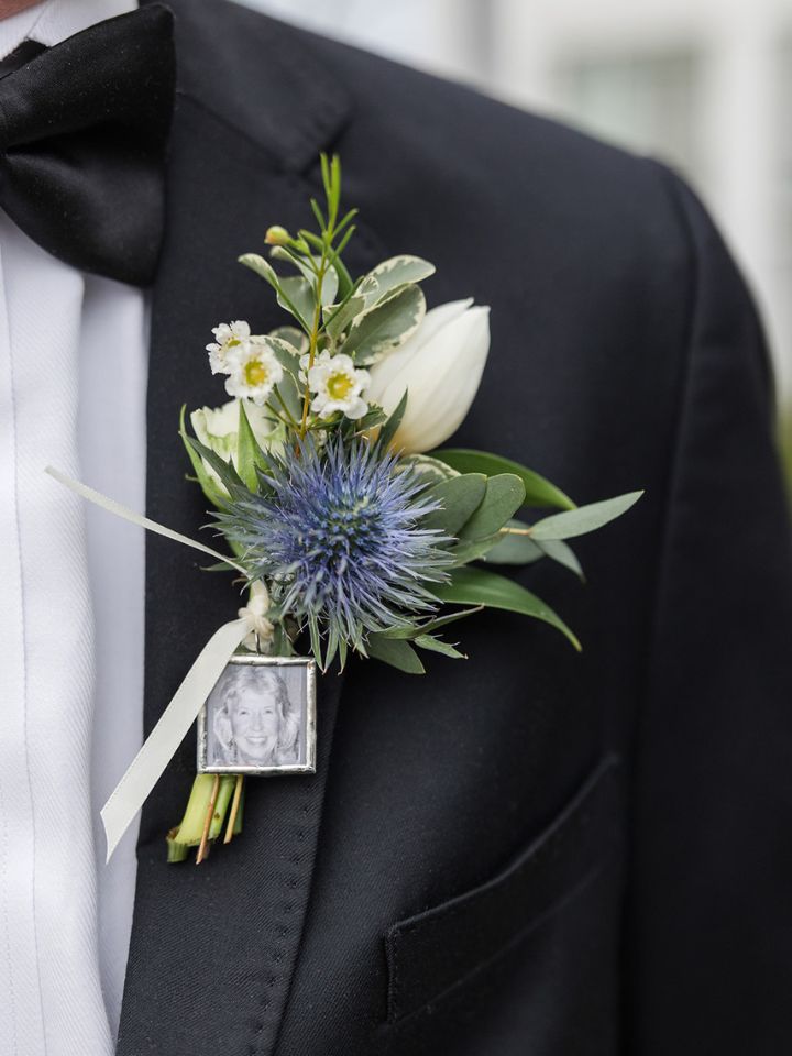 blue and white boutonniere Black suit jacket with a blue and white boutonniere, with a small photo charm on the ribbon.