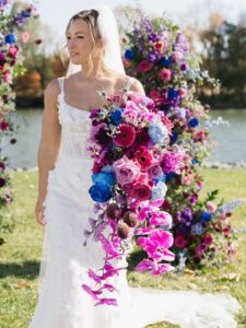cascading kati showstopper Bride holds large bouquet in purples and blues with long cascading orchids.