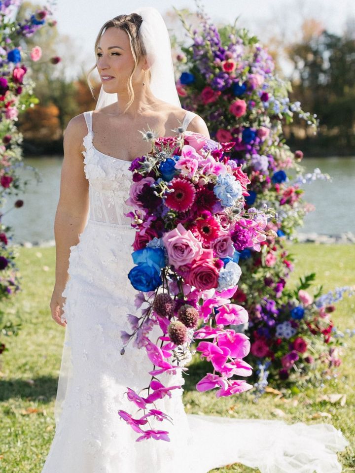 cascading kati showstopper Bride holds large bouquet in purples and blues with long cascading orchids.