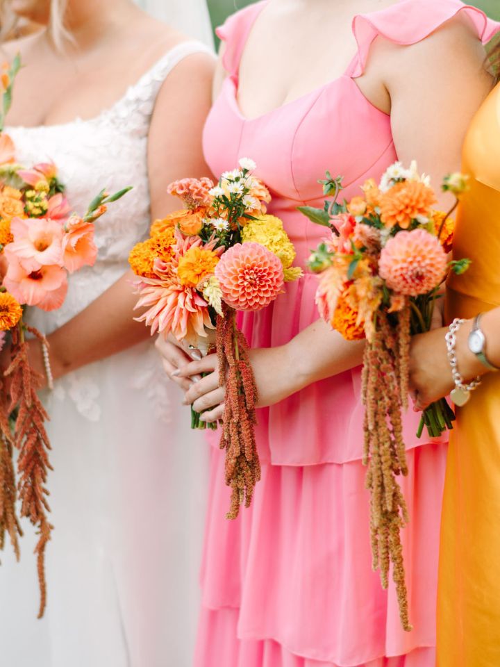 dahlia amaranth bridesmaids Bright pink and orange dresses on bridesmaids, holding bouquets with dahlias and amaranth