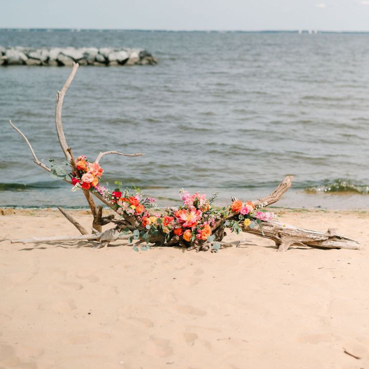 Beach wedding with driftwood pieces and coral florals.